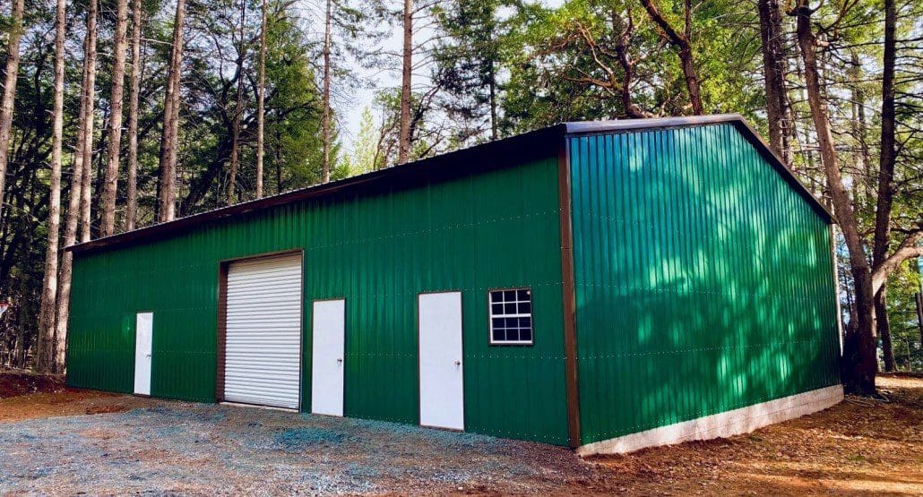 A large green steel garage with three small white doors