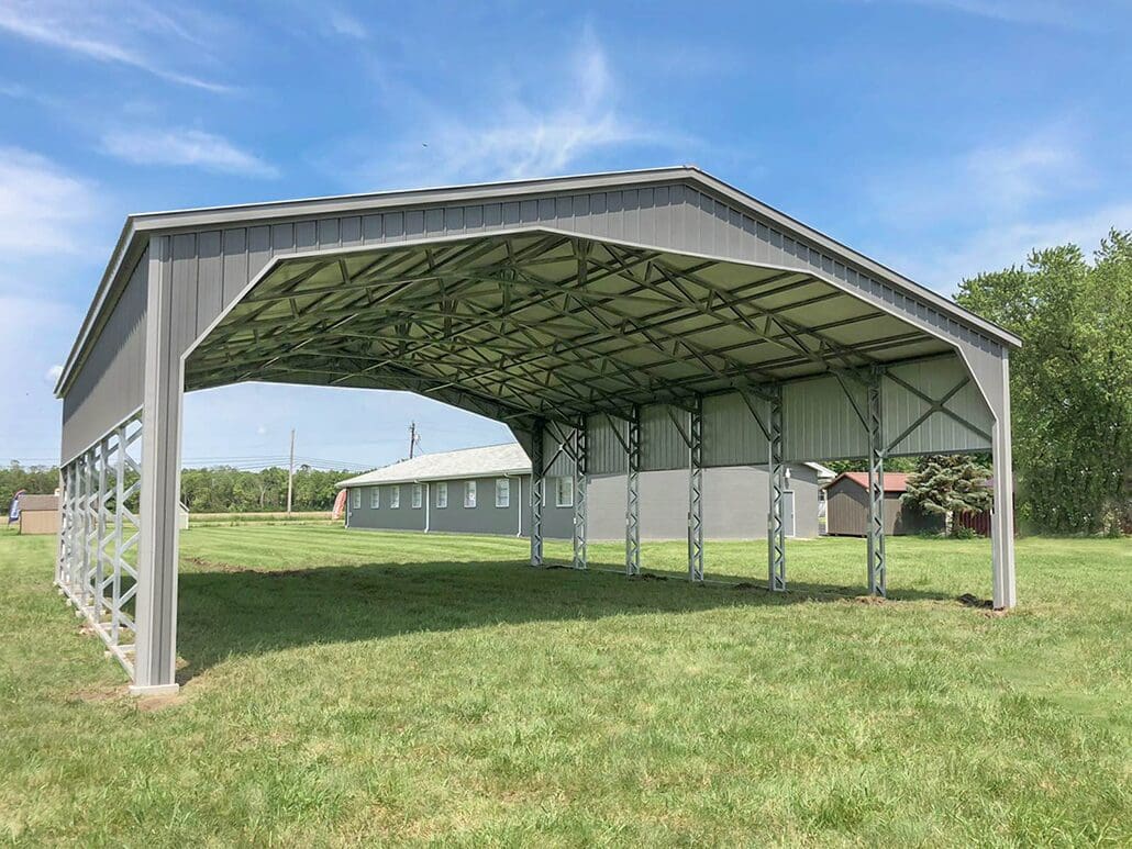 A wide steel carport on a grass field