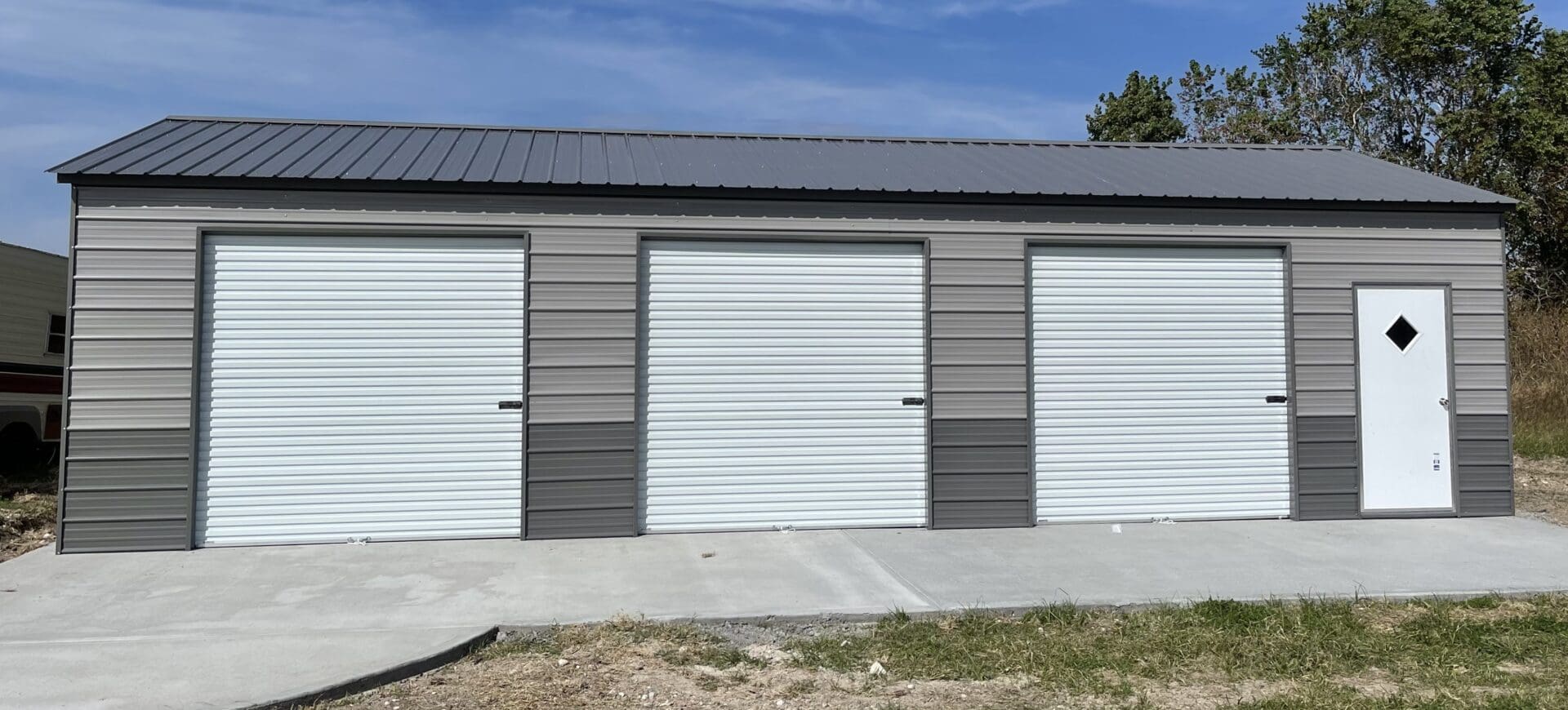 A steel garage in gray tones with three white doors