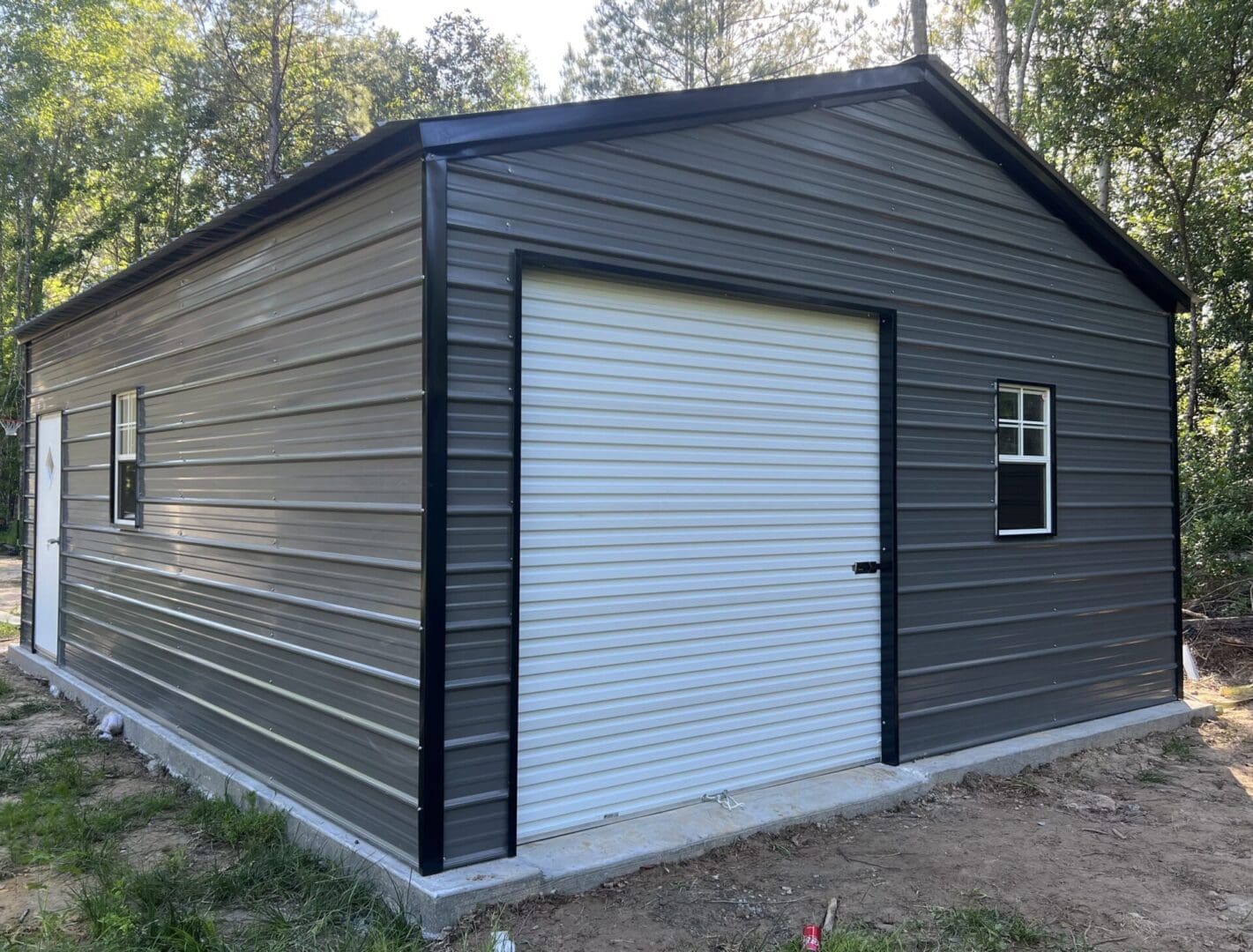 A small dark gray steel garage with a white door