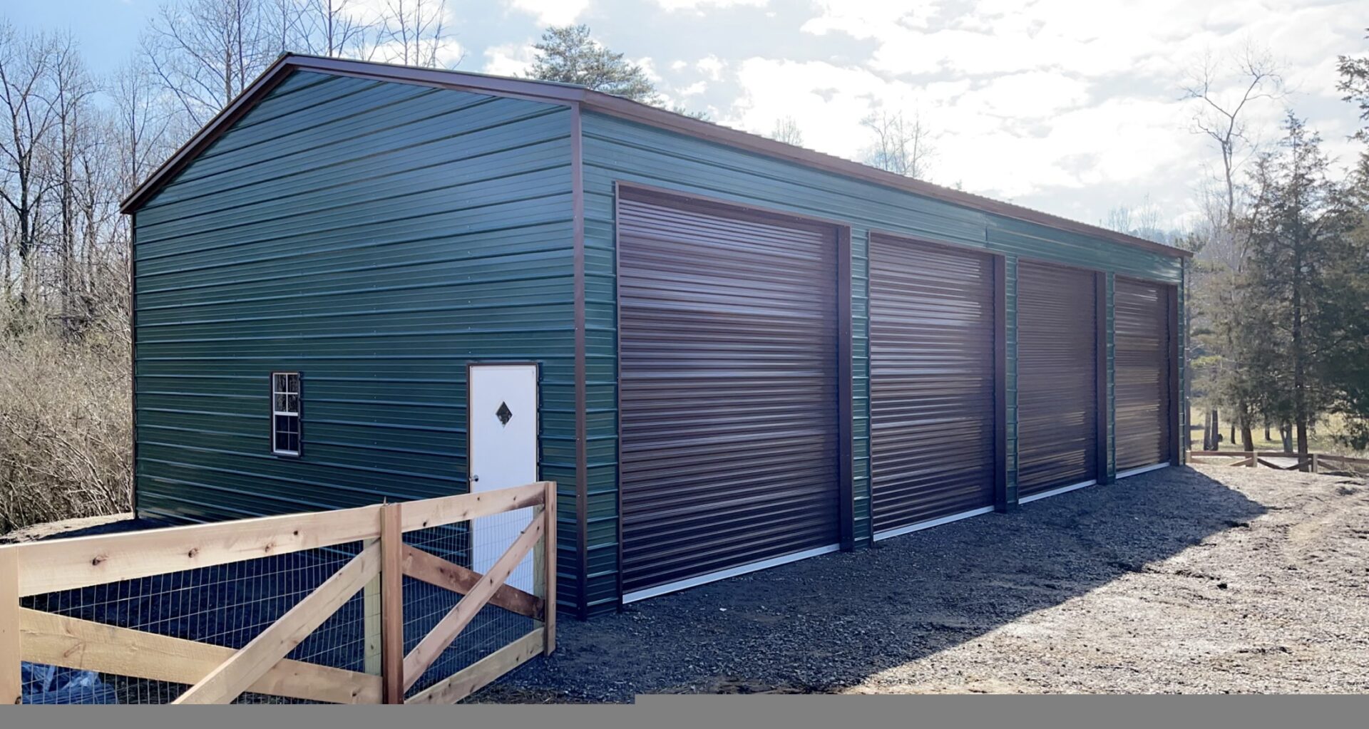 A green metal garage with two doors and trees in the background